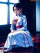 A woman in a white kimono sitting on a wooden floor.