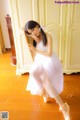 A woman in a white dress sitting on a chair.