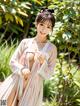 A woman in a white and pink kimono posing for a picture.