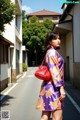 A woman in a purple and orange kimono is walking down the street.