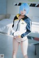A woman with blue hair wearing a white and yellow jacket.