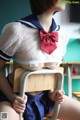 A woman in a school uniform sitting on a chair.