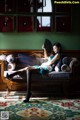 A woman sitting on a couch holding a fan.