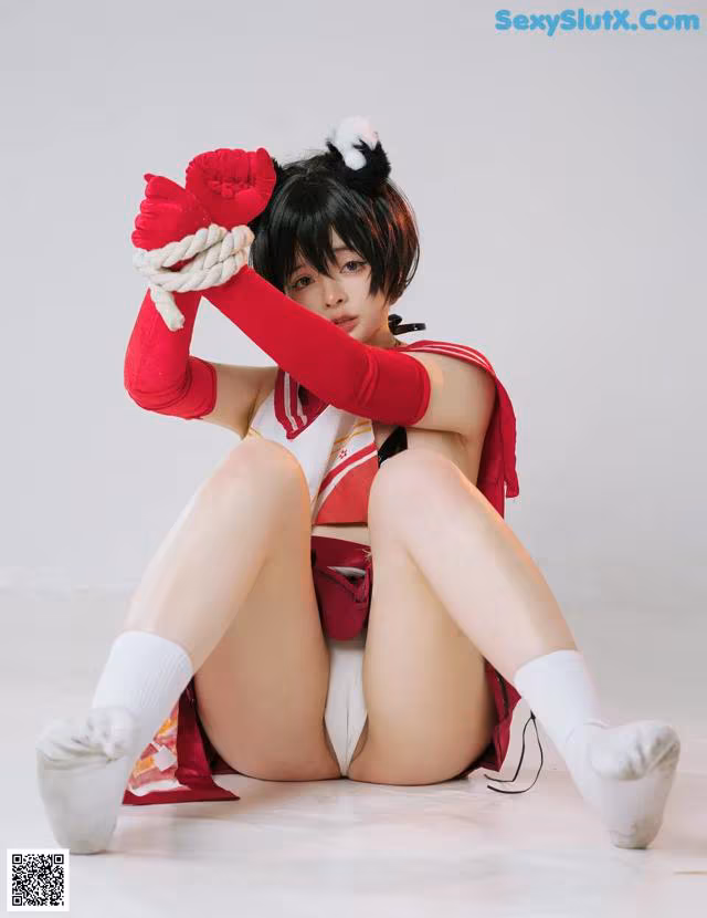 A woman in a red and white outfit is sitting on the floor.