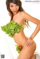 A woman in a green bikini holding a bunch of lettuce.