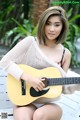 A woman sitting on a bench holding a guitar.