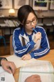 A woman sitting at a table with a pen in her mouth.