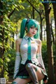 A woman with green hair sitting on a bench in the woods.