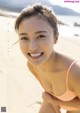 A woman in a pink bikini sitting on a beach.