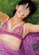 A woman laying on the grass in a purple bra and skirt.