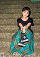 A young woman sitting on the steps of a building holding a pair of shoes.