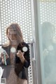 A woman standing in front of a glass door looking at her cell phone.