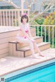 A woman in a pink bikini sitting on the edge of a pool.