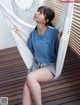 A woman sitting in a hammock on a wooden deck.