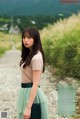 A woman in a green skirt standing on a dirt road.