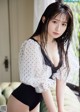 A woman in a white blouse and black panties posing on a couch.