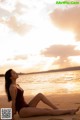 A woman in a red bathing suit sitting on the beach.