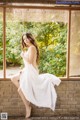 A woman in a white dress sitting on a window sill.