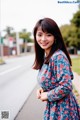 A woman in a blue dress standing on the side of a road.